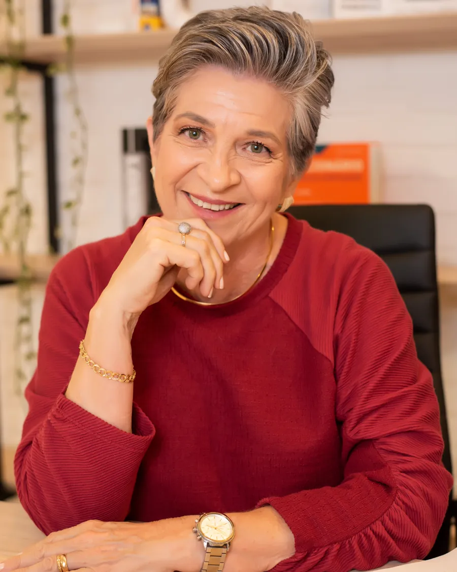 Professora Marta Garcia sorrindo, sentada à mesa de trabalho