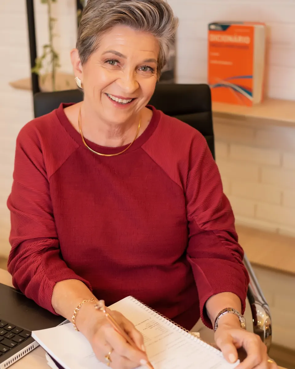Professora Marta Garcia à mesa, corrigindo um texto